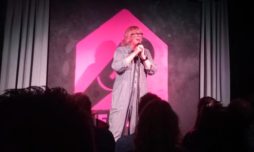A female comedian with pink hair on stage