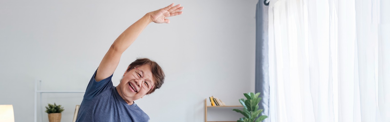 A woman in her 50s stretches at home, smiling