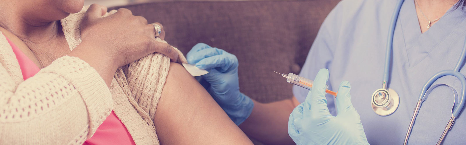 Nurse giving a flu jab to a woman